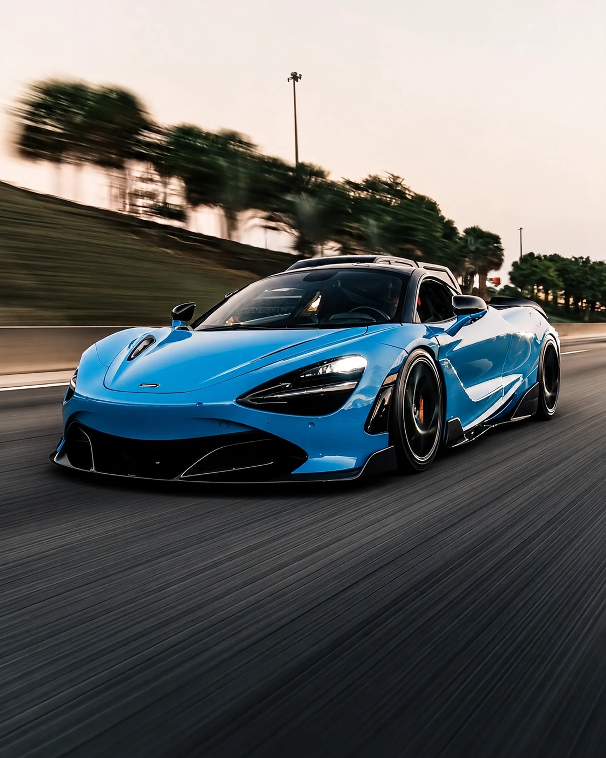 Blue McLaren 720S in motion on a highway at dusk