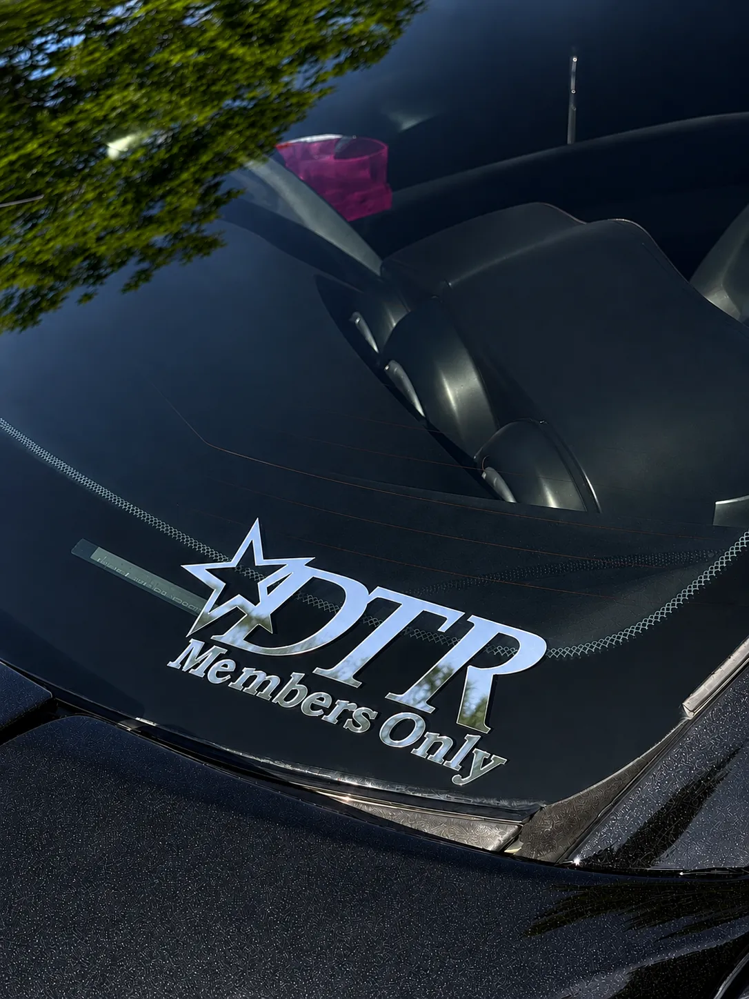 DTR Members Only decal on the spotless rear glass of a gloss black Nissan 350Z