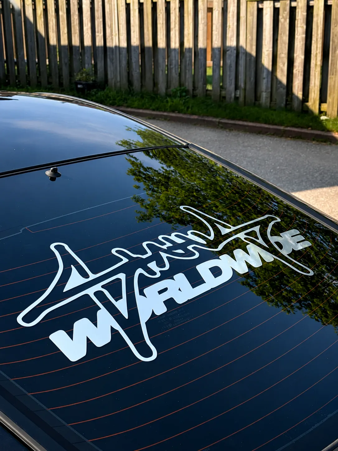 Worldwide club decal on the streak-free rear window of a black Nissan 350Z