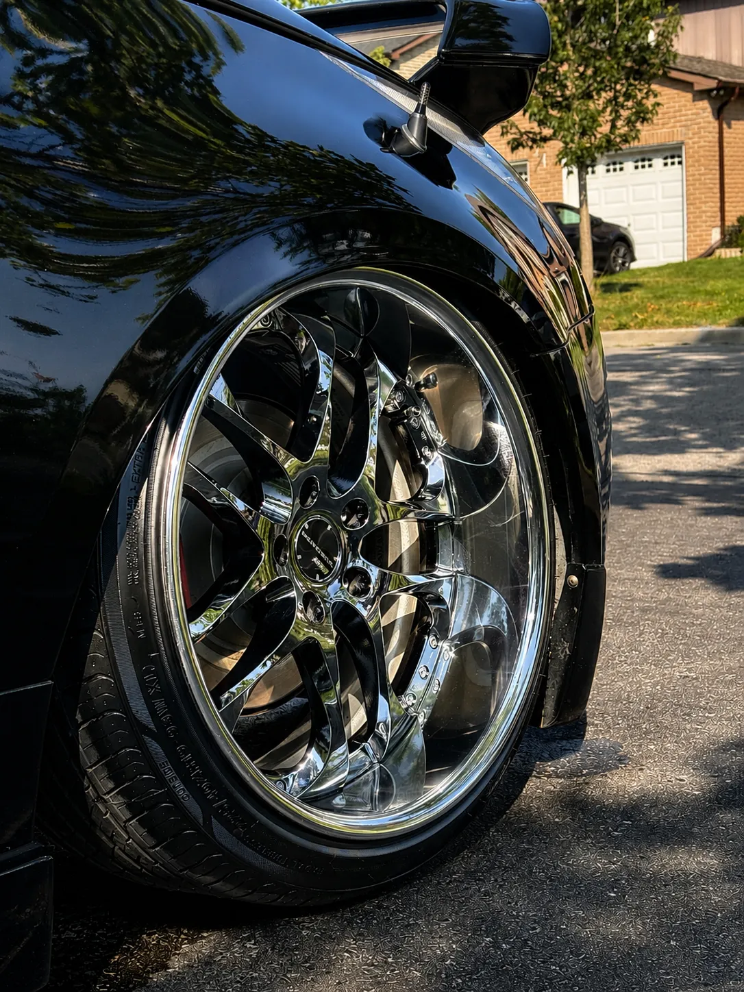 Low-angle view of a polished chrome 350Z wheel and gloss black fender