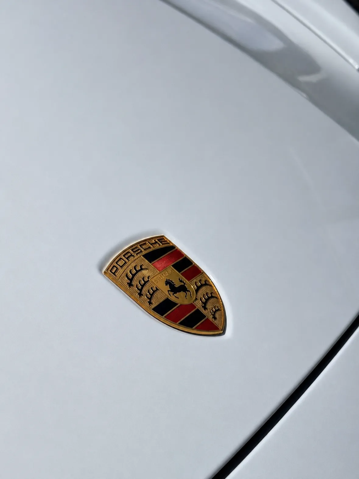 Porsche crest on a freshly detailed white hood