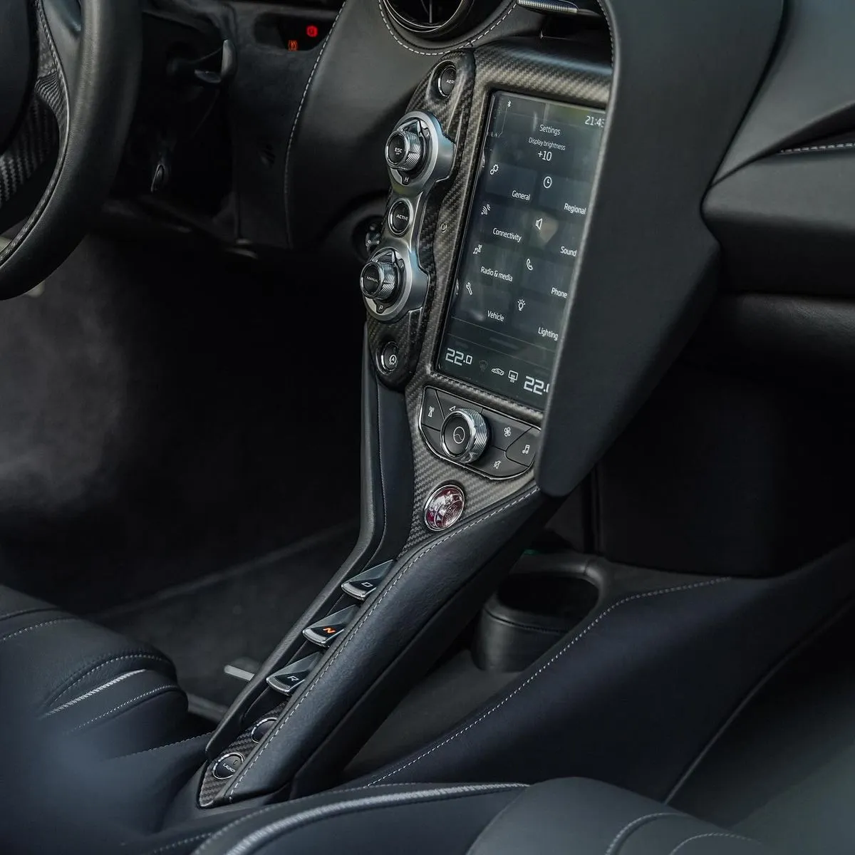 Carbon fibre centre console and switchgear of a supercar interior, spotless after detailing