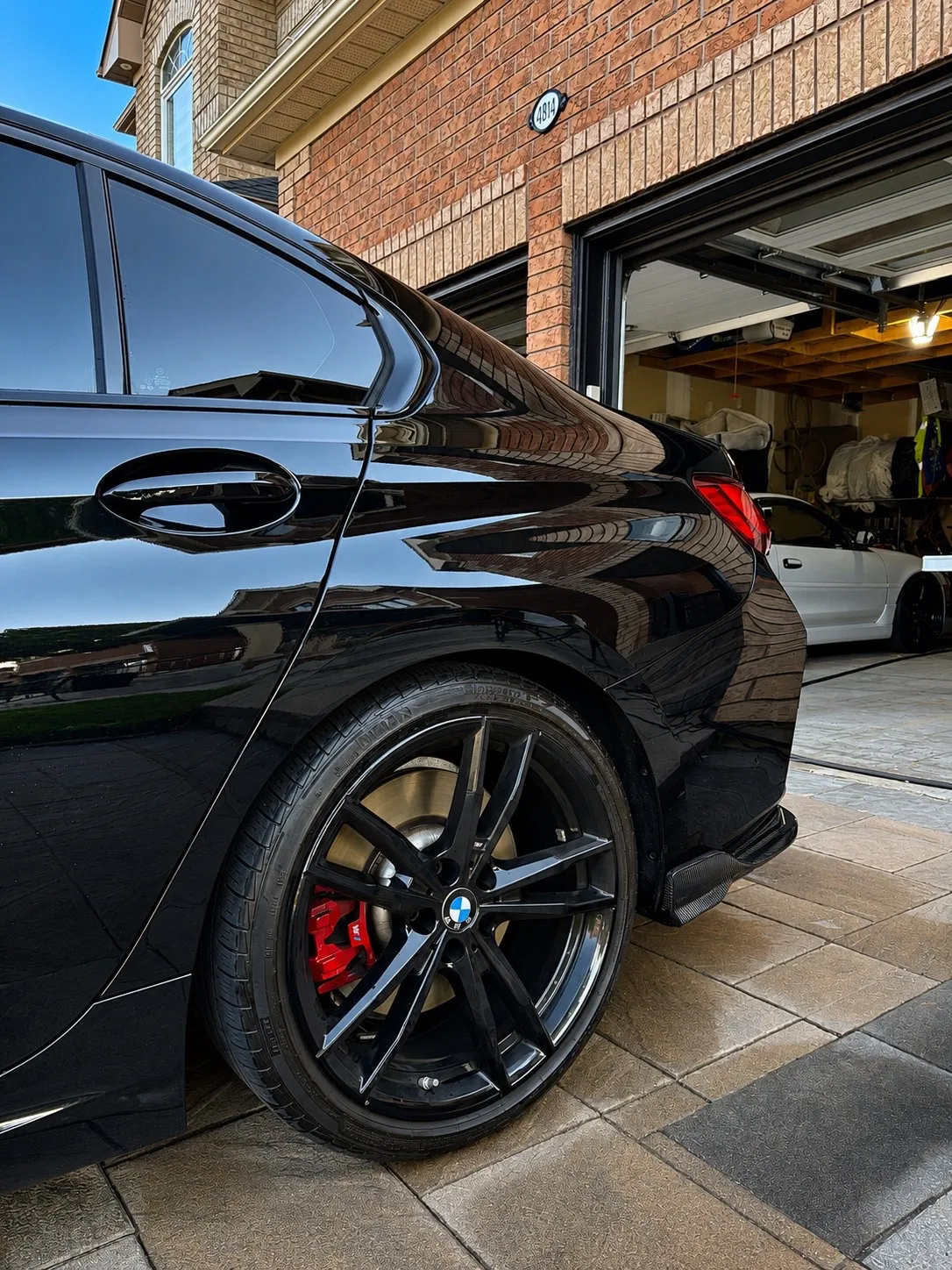 Gloss black BMW M340i rear quarter with mirror reflections in evening light after a full detail